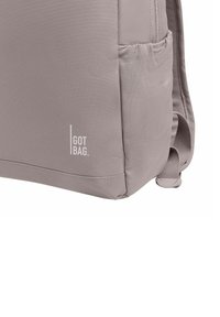 Grå tygryggsäck med texturerad yta, sidoficka och logotypen "I GOT BAG" i vitt. Har justerbara remmar och förstärkta sömmar.