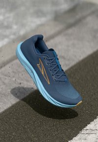 Chaussure de course en maille bleu marine avec une semelle intermédiaire bleu clair. Équipée de lacets turquoise et d'un logo orange. Légère, conçue pour le confort et le soutien.