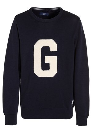 Navy knitted sweater featuring a large cream "G" patch on the front. Ribbed neckline and cuffs, with a tag on the lower side.