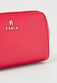 Red textured leather zippered pouch with gold Furla logo and gold zipper on a white background.