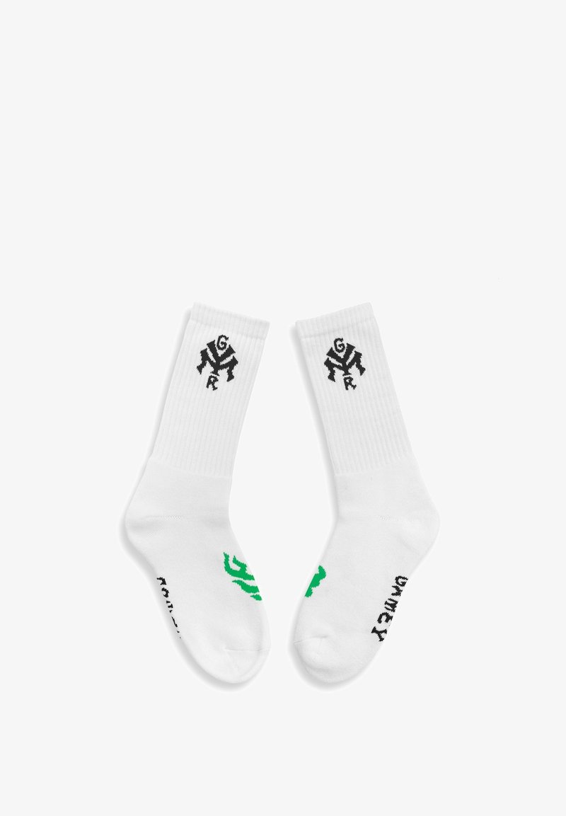 Calcetines de crew blancos con textura acanalada, que presentan logotipos y textos en negro y verde. El diseño incluye detalles gráficos en el puño y la suela.