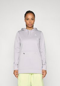 Hellgrauer Hoodie mit Kängurutasche, Kapuze mit Kordelzug und dezentem Logo auf der Brust, kombiniert mit leuchtend gelben Shorts.