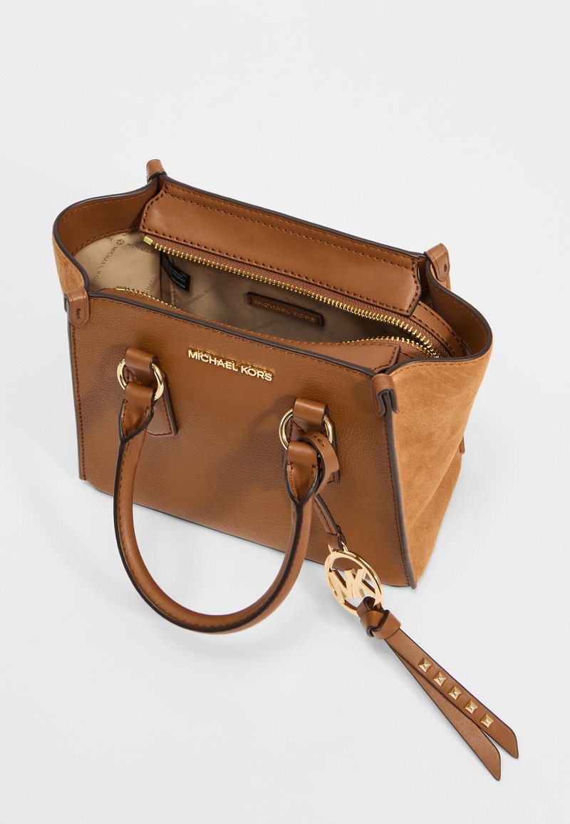 Sac à main en cuir marron avec des accents en suède, quincaillerie dorée, double poignées et une étiquette porte-clés. L'intérieur comprend une poche zippée.