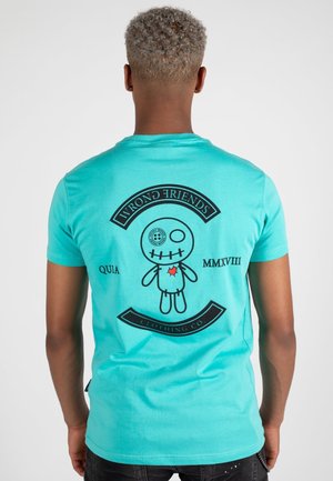Turquoise cotton t-shirt featuring a black graphic on the back with a doll design, text "WRONG FRIENDS," and circular accents.