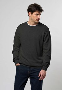 Tummanharmaa neulepusero, jossa pyöreä pääntie, resorireunukset hihoissa ja helmassa. Pienellä logolla rinnassa, yhdistetty farkkuihin.