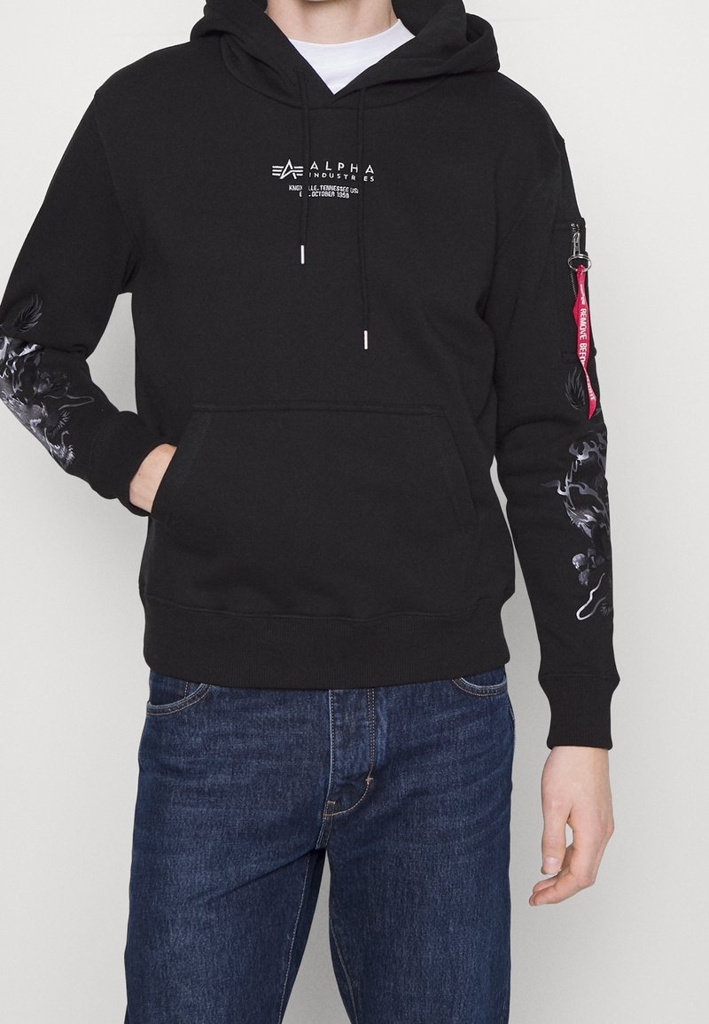 Sweat à capuche noir en coton, avec une poche avant, une capuche à cordon, un logo sur la poitrine et des motifs graphiques sur les manches.