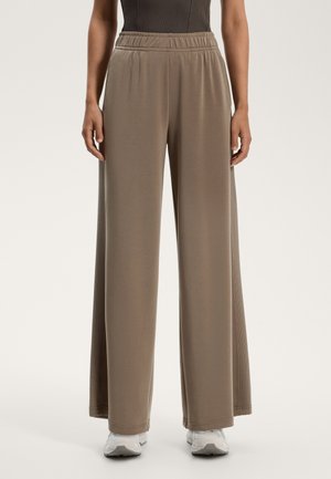 Lange, beige broek van zacht materiaal met een elastische tailleband. Heeft een ontspannen pasvorm en een gladde textuur. Geen zichtbare patronen of accenten.
