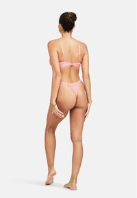 Roze lingerieset met een bralette met verstelbare bandjes en een bijpassende string. Gemaakt van een soepele stof met logo-accenten.