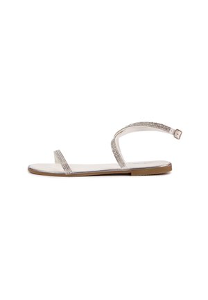 Flat sandals with two narrow, shimmering silver straps and a buckled ankle strap. The sole is light brown with a smooth finish.