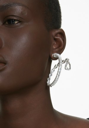 Grande boucle d'oreille en argent avec un ornement en pierre précieuse transparente, un bandeau texturé, et un accent en goutte pendante.