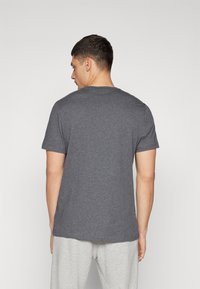 T-shirt in cotone grigio con maniche corte e scollatura rotonda, mostrata di schiena. Tessuto liscio; design leggermente aderente.