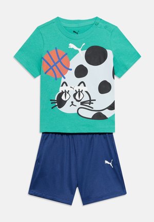 Grøn kortærmet skjorte med grafik af sort og hvid kat og orange basketball, kombineret med blå træningsshorts med Puma-logo.
