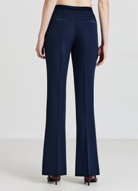 Marineblaue, ausgestellte Hosen mit glatter Textur, ausgestattet mit zwei Gesäßtaschen und einem figurbetonten Bund, entworfen für eine elegante Silhouette.