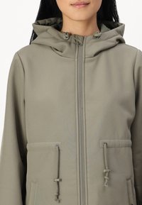Svijetlo sivi zip-up sako s kapuljačom, detaljima na vezivanje i prednjim džepovima od glatkog, teksturiranog materijala.
