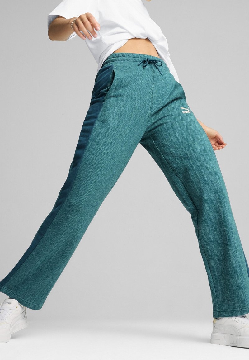 Pantaloni sportivi teal a spina di pesce con vita con cordino, tasche laterali e logo bianco. Abbinati a scarpe bianche, con design a gamba ampia.
