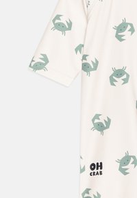 Light-colored short-sleeve shirt featuring a repeating crab pattern in green, with the text "OH CRAB" in bold black near the hem.