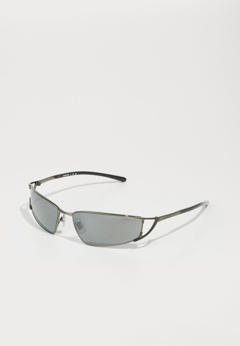 Lunettes de soleil avec une monture métallique élégante, des verres teintés gris, une forme allongée et des branches noires. Design minimaliste et construction légère.