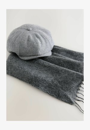 Grijze wollen muts met een ronde bovenkant en gestikte panelen, gecombineerd met een donkergrijze sjaal met een zachte textuur en franjes aan de randen.