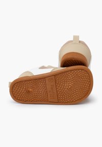 Zapatillas infantiles con un diseño en tonos marrón y blanco, con una suela de goma texturizada, un upper suave y un bucle en la parte trasera para facilitar su uso.