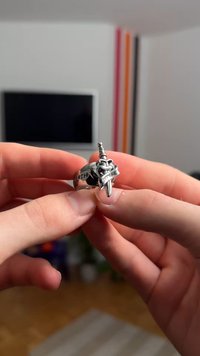 Silverring med ett svärdsmotiv och en banderoll med texten "DEATH BEFORE." Ringen har en polerad yta och ett tjockt band.