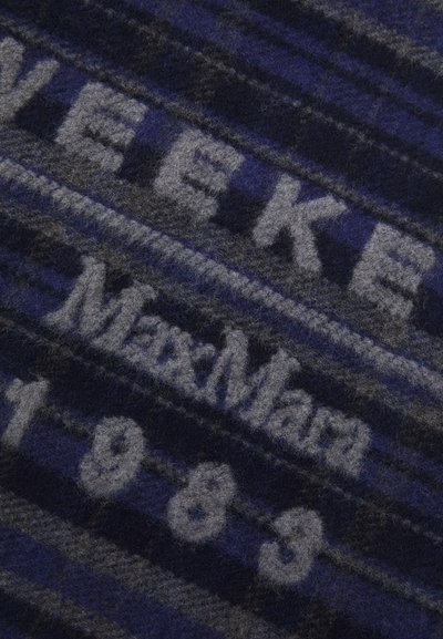 Villane pleed, millel on tekstuuriga tume sinine ja hall triibuline muster, millel on kontrastsete tähtedega kirjutatud "MaxMara" ja "1983".