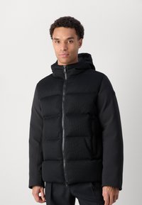 Black puffer jacket with a ribbed texture on the upper half, smooth sleeves, a zipper, and a hood. No visible patterns or logos.