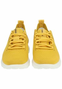 Gelbe Sportschuhe mit einem strukturierten Strick-Obermaterial, passenden gelben Schnürsenkeln und weißen Gummisohlen. Verfügt über Zuglaschen an der Ferse für ein einfaches Anziehen.