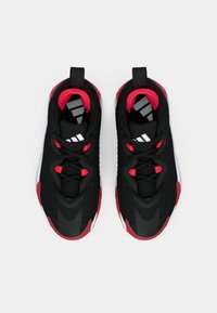O pereche de încălțări atletice negre și roșii, cu tălpi albe, șireturi și logo Adidas, văzute din perspectiva de sus pe un fond alb.