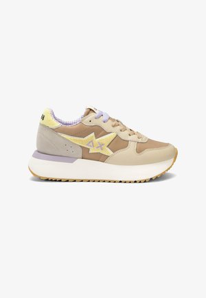 Sneaker beige e sabbia con stella gialla e logo "AX", lacci beige e viola, suola bianca spessa e collarino imbottito al tallone con testo.