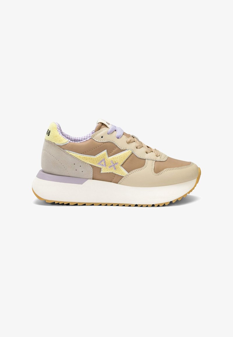 Baskets beige et sable avec étoile jaune et logo "AX", lacets beige et violet, semelle blanche épaisse et col de talon rembourré avec texte.
