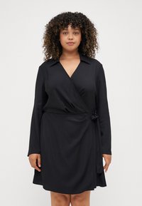 Abito avvolgente nero con maniche lunghe, colletto e dettaglio in vita annodato. Tessuto liscio, lunghezza al ginocchio, design minimalista, senza motivi visibili.