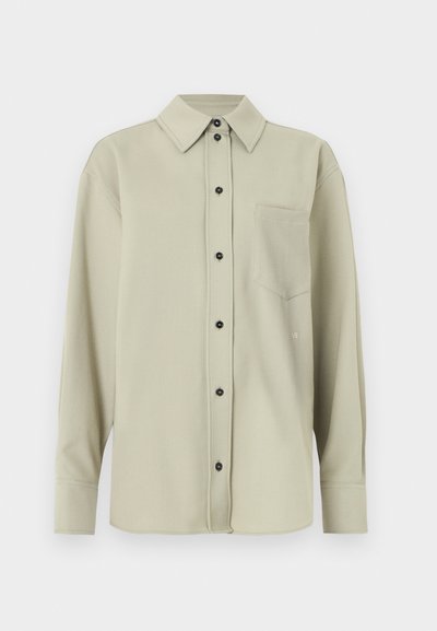 Ανοιχτό πράσινο, μακρυμάνικο πουκάμισο με κουμπιά εμπρός, μία τσέπη στο στήθος και μαύρα κουμπιά. Ομαλή υφή και κλασικός γιακάς.