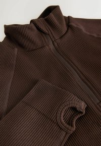 Brown ribbed pullover with a high collar, featuring a half-zip closure and thumbholes at the sleeves, textured fabric detail throughout.