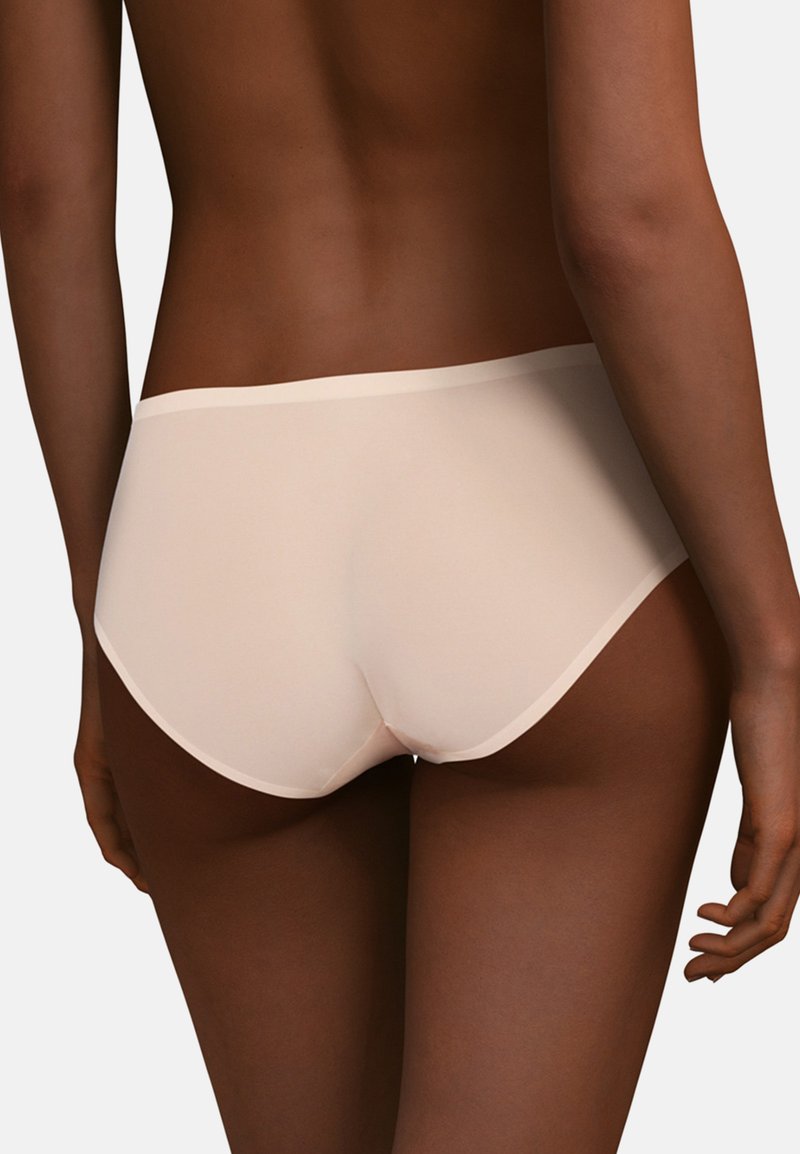 Nahtlose beige Pantys mit glatter Textur und niedrigem Taillenbund, ausgestattet mit einem dezenten, elastischen Bund und klassischem Schnitt.