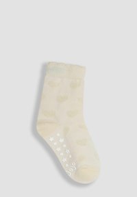 Calcetín color crema con patrones de corazones, puño acanalado y agarres antideslizantes en forma de estrella blanca en la suela. Textura suave, diseño hasta el tobillo.