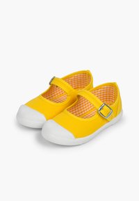 Zapatillas de lona amarillas con suela de goma blanca, estilo Mary Jane, que presentan un hebilla lateral y un forro interior de cuadros vichy.