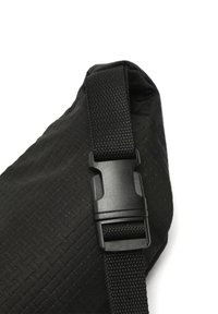 Czarna torba na ramię o plecionym wzorze, z mocną czarną klamrą i regulowanym paskiem. Materiał jest lekki i wytrzymały.