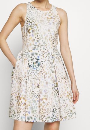 Mouwloze jurk met bloemenpatroon van lichte stof, met een nauwsluitend lijfje, geplooide rok en zakken. Kleuren omvatten zachte pasteltinten en groentinten.