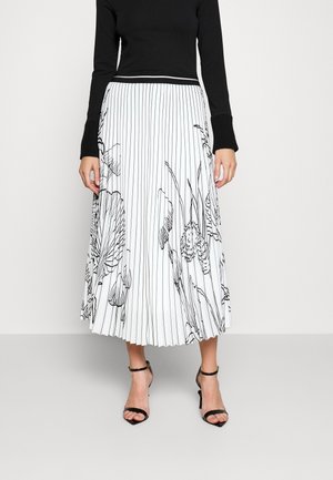 Black long-sleeve top paired with white pleated midi skirt featuring black vertical stripes and floral outlines, worn with black ankle-strap heels.