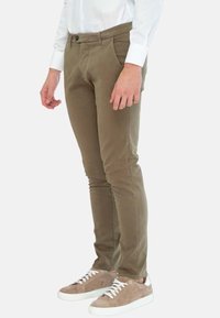 Pantaloni slim-fit color khaki con una texture liscia, design a cinque tasche e chiusura con bottone, abbinati a sneaker in suede marrone chiaro.