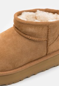 Stivaletto in suede marrone con fodera interna morbida e pelosa e suola in gomma texturizzata. Collo arrotondato con dettagli cuciti.