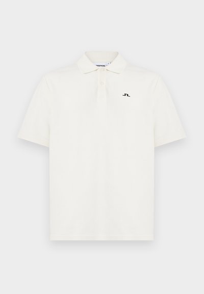 Λευκό πόλο με κοντά μανίκια, γιακά, δύο κουμπιά και μικρό μαύρο λογότυπο στο αριστερό στήθος.