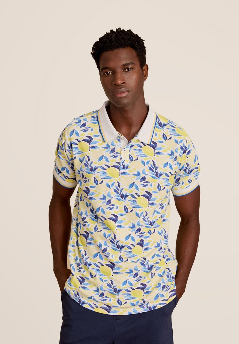 Korte mouwen polo in geel met een bloemenpatroon van citroenen en blauwe bladeren. Witte kraag met blauwe rand, gemaakt van katoen.