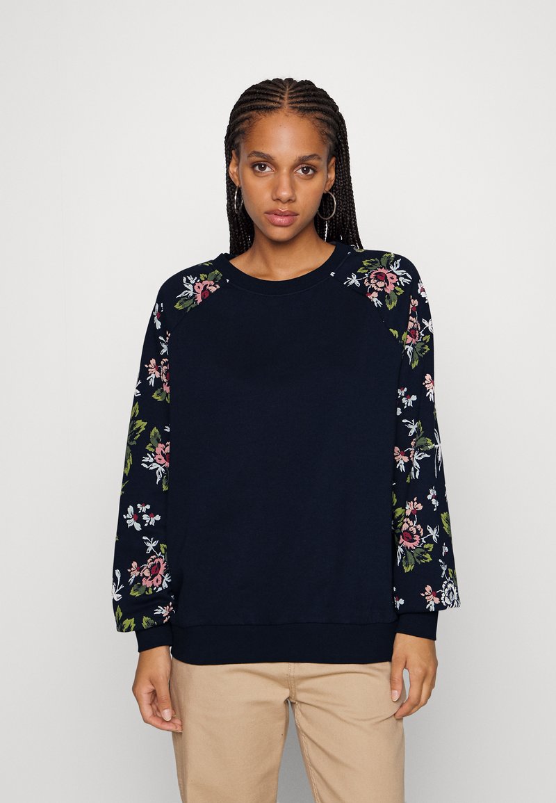 Navy sweatshirt with floral pattern on sleeves. Made of soft fabric, featuring a round neckline and ribbed cuffs. Relaxed fit.