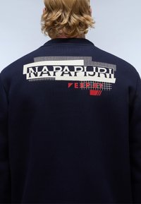 Marine sweatshirt met een grote witte en rode grafische print op de achterkant. Zachte textuur met geribde kraag en details, casual pasvorm.