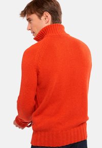 Strickpullover in Orange mit hohem Kragen sowie gerippten Bündchen und Saum. Die Textur ist weich und das Design zeigt eine taillierte Silhouette.