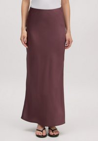 Maxi rok in diep bordeauxrood, gladde textuur, aansluitende taille, enkel-lang, gecombineerd met zwarte slippers voor een casual look.