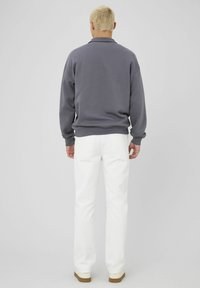Sweatshirt gris avec un col, des poignets et un ourlet côtelés, associé à un pantalon blanc à jambe droite et des chaussures beiges. Conception simple et moderne.