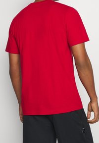 Rode katoenen t-shirt met korte mouwen, een ronde halslijn en een rechte snit. De achterkant heeft een gladde textuur zonder extra details.