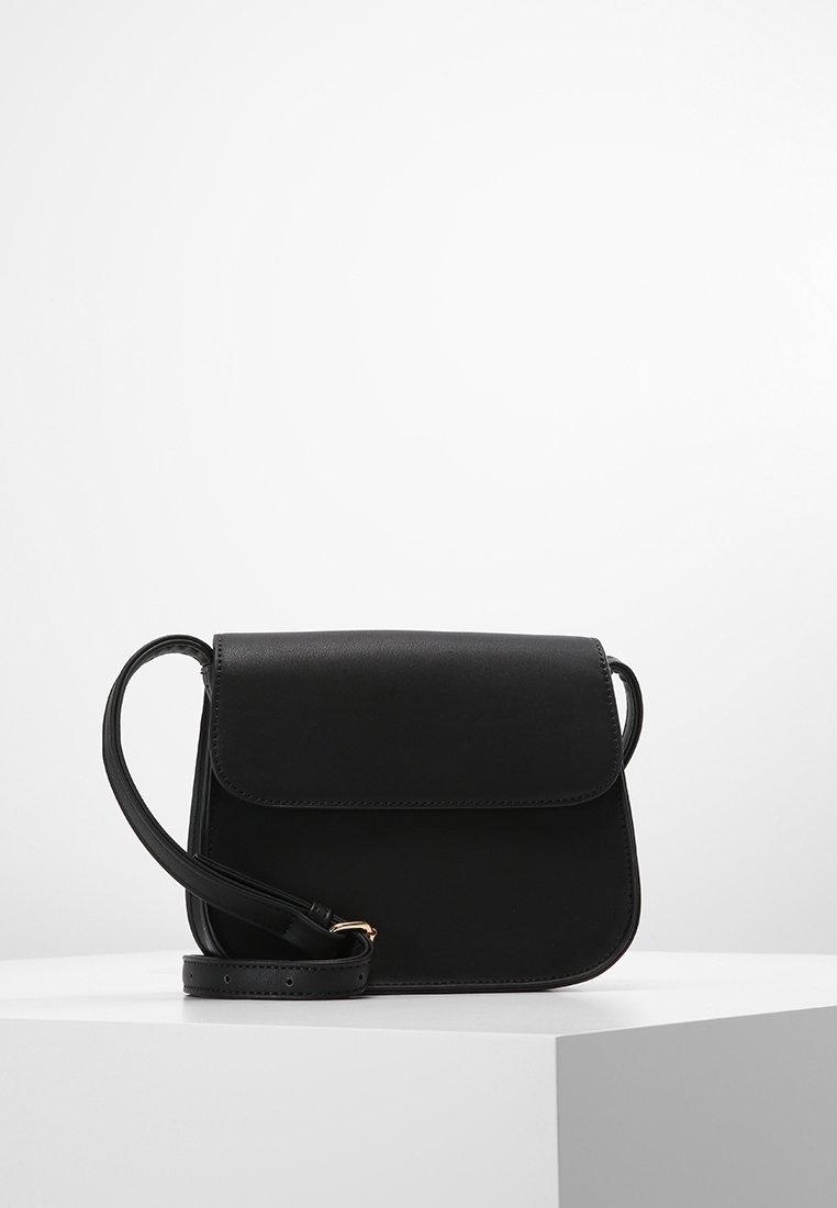 Černá kožená taška přes rameno s předním klopovým uzávěrem, nastavitelným popruhem, zaoblenými rohy a jemným prošíváním. Jednoduchý a funkční design.